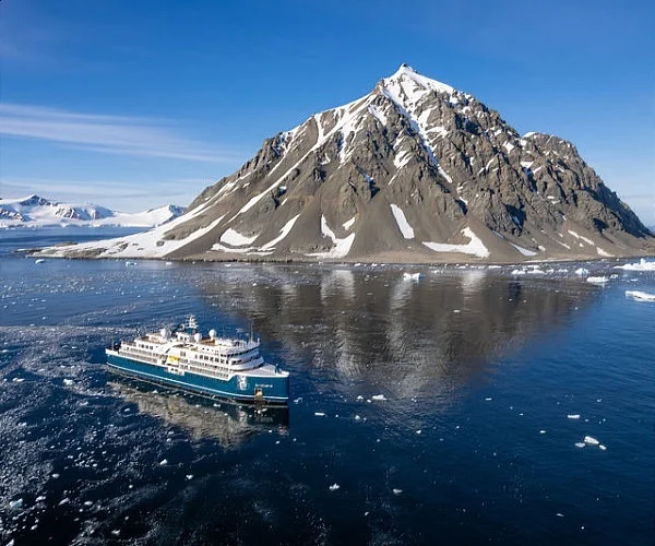 SH Minerva sailing past a volcanic mountain landscape